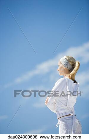 Young woman standing with eyes closed and arms crossed, side view, sky in background View Large Photo Image Stock Photo - Young woman standing with eyes closed and arms crossed, side view, sky in background. Fotosearch