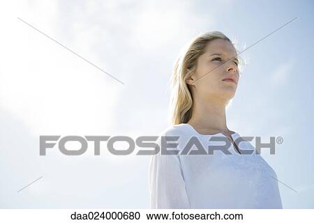 Young woman standing with sky in background, low angle view View Large Photo Image Stock Image - Young woman standing with sky in background, low angle view. Fotosearch