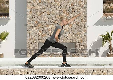 Stock Photo - Young woman stretching legs outdoors. Fotosearch