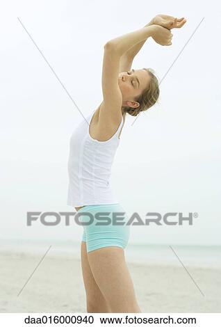Young woman stretching on beach View Large Photo Image Stock Image - Young woman stretching on beach. Fotosearch