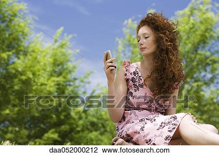 Young woman text messaging outdoors View Large Photo Image Stock Image - Young woman text messaging outdoors. Fotosearch