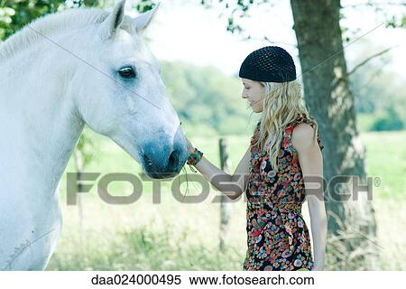 Young woman touching horse, side view View Large Photo Image Stock Photography - Young woman touching horse, side view. Fotosearch