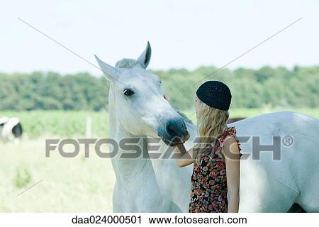 Young woman touching horse View Large Photo Image Stock Image - Young woman touching horse. Fotosearch