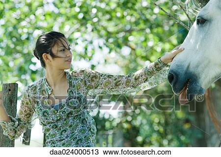 Young woman touching horse View Large Photo Image Stock Image - Young woman touching horse. Fotosearch