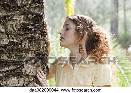 Young woman touching tree trunk View Large Photo Image Picture - Young woman touching tree trunk. Fotosearch