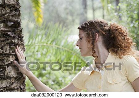 Young woman touching tree trunk View Large Photo Image Stock Image - Young woman touching tree trunk. Fotosearch
