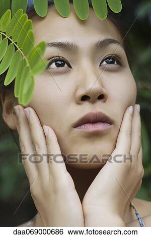 Young woman under leaves, looking up View Large Photo Image Stock Photograph - Young woman under leaves, looking up. Fotosearch