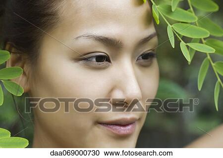 Stock Image - Young woman under leaves. Fotosearch