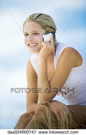 Young woman using cell phone outdoors, smiling View Large Photo Image Stock Photo - Young woman using cell phone outdoors, smiling. Fotosearch