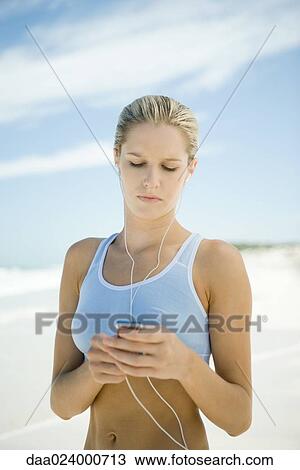 Young woman using MP3 player on beach, wearing active wear View Large Photo Image Stock Image - Young woman using MP3 player on beach, wearing active wear. Fotosearch