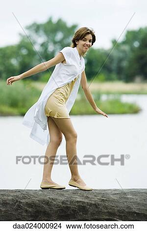 Young woman walking across log with arms out, smiling at camera View Large Photo Image Picture - Young woman walking across log with arms out, smiling at camera. Fotosearch