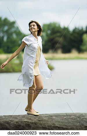 Young woman walking across log with arms out, looking up View Large Photo Image Stock Image - Young woman walking across log with arms out, looking up. Fotosearch