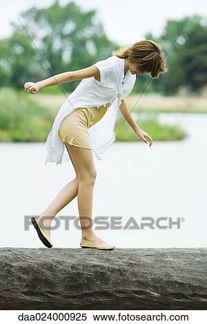 Young woman walking across log with arms out, looking down View Large Photo Image Stock Photography - Young woman walking across log with arms out, looking down. Fotosearch