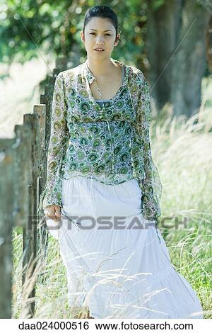 Young woman walking beside rural fence, looking at camera View Large Photo Image Stock Photograph - Young woman walking beside rural fence, looking at camera. Fotosearch