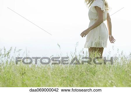 Young woman walking in meadow, cropped View Large Photo Image Stock Image - Young woman walking in meadow, cropped. Fotosearch