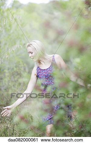 Young woman walking in nature, touching tall grass View Large Photo Image Stock Image - Young woman walking in nature, touching tall grass. Fotosearch
