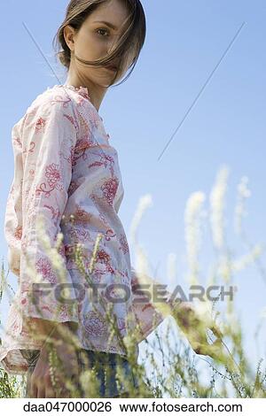 Young woman walking in tall grass, hair tousled by breeze View Large Photo Image Stock Photograph - Young woman walking in tall grass, hair tousled by breeze. Fotosearch