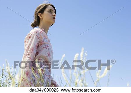 Young woman walking in tall grass, looking up View Large Photo Image Stock Image - Young woman walking in tall grass, looking up. Fotosearch
