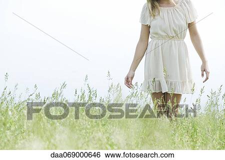 Young woman walking in tall grass, cropped View Large Photo Image Stock Photograph - Young woman walking in tall grass, cropped. Fotosearch