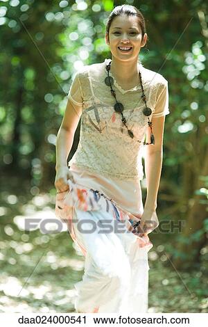 Young woman walking in woods, lifting skirt, smiling at camera View Large Photo Image Stock Image - Young woman walking in woods, lifting skirt, smiling at camera. Fotosearch