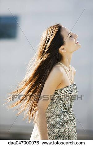 Young woman walking outdoors, long hair tousled by wind View Large Photo Image Stock Photograph - Young woman walking outdoors, long hair tousled by wind. Fotosearch