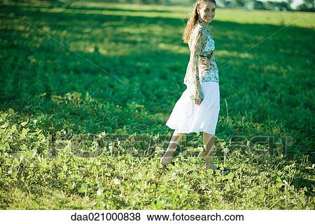 Young woman walking through field, smiling at camera View Large Photo Image Stock Photo - Young woman walking through field, smiling at camera. Fotosearch
