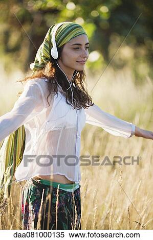 Young woman walking through field, listening to headphones View Large Photo Image Stock Photography - Young woman walking through field, listening to headphones. Fotosearch