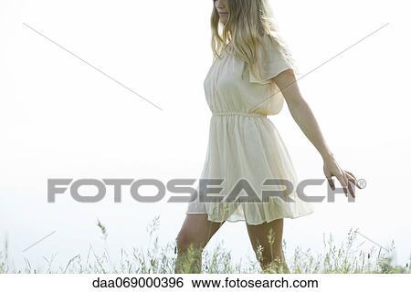 Young woman walking through tall grass View Large Photo Image Stock Photograph - Young woman walking through tall grass. Fotosearch