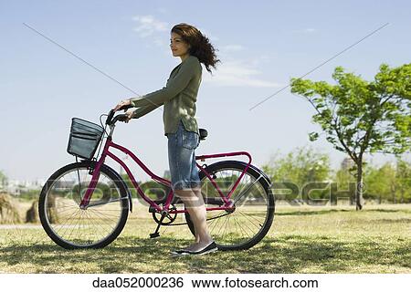 Young woman walking with bicycle in park View Large Photo Image Stock Photograph - Young woman walking with bicycle in park. Fotosearch