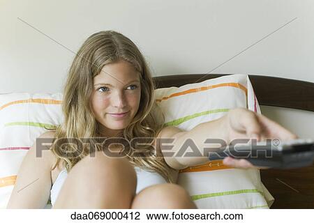 Young woman watching TV in bed View Large Photo Image Stock Image - Young woman watching TV in bed. Fotosearch