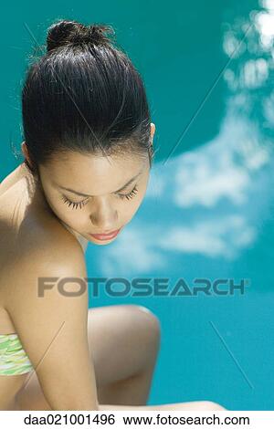 Stock Photograph - Young woman wearing bathing suit, pool in background, high angle view. Fotosearch