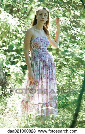 Young woman wearing dress, standing in woods View Large Photo Image Stock Photo - Young woman wearing dress, standing in woods. Fotosearch