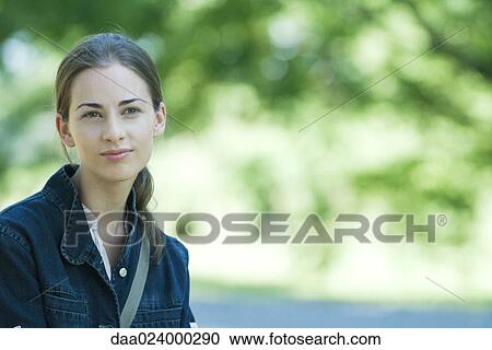 Young woman wearing jacket, outdoors, smiling at camera, focus on foreground View Large Photo Image Stock Image - Young woman wearing jacket, outdoors, smiling at camera, focus on foreground. Fotosearch