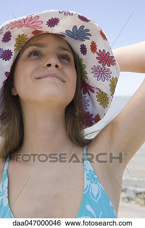 Young woman wearing sun hat at beach, looking up, smiling, portrait View Large Photo Image Stock Photograph - Young woman wearing sun hat at beach, looking up, smiling, portrait. Fotosearch