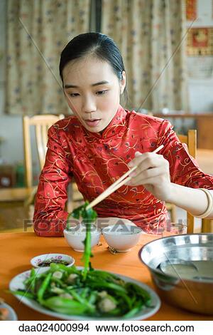 Young woman wearing traditional Chinese clothing, eating with chopsticks View Large Photo Image Picture - Young woman wearing traditional Chinese clothing, eating with chopsticks. Fotosearch