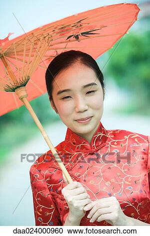 Young woman wearing traditional Chinese clothing, holding parasol, portrait View Large Photo Image Stock Image - Young woman wearing traditional Chinese clothing, holding parasol, portrait. Fotosearch