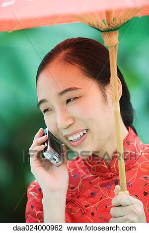 Young woman wearing traditional Chinese clothing, holding parasol and using cell phone View Large Photo Image Stock Image - Young woman wearing traditional Chinese clothing, holding parasol and using cell phone. Fotosearch