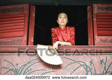 Young woman wearing traditional Chinese clothing, holding fan, leaning on windowsill View Large Photo Image Stock Image - Young woman wearing traditional Chinese clothing, holding fan, leaning on windowsill. Fotosearch