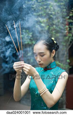 Young woman wearing traditional Chinese clothing, holding up incense View Large Photo Image Stock Image - Young woman wearing traditional Chinese clothing, holding up incense. Fotosearch