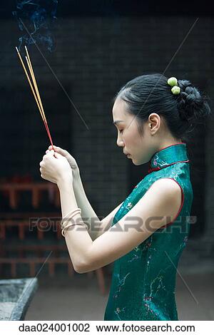 Young woman wearing traditional Chinese clothing, holding up incense, side view View Large Photo Image Stock Image - Young woman wearing traditional Chinese clothing, holding up incense, side view. Fotosearch