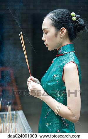 Young woman wearing traditional Chinese clothing, holding up incense, side view View Large Photo Image Stock Image - Young woman wearing traditional Chinese clothing, holding up incense, side view. Fotosearch