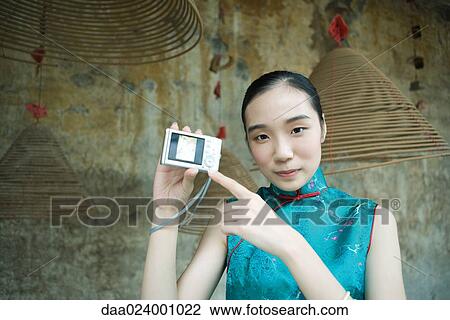 Young woman wearing traditional Chinese clothing, holding up digital camera, pointing to screen View Large Photo Image Stock Image - Young woman wearing traditional Chinese clothing, holding up digital camera, pointing to screen. Fotosearch