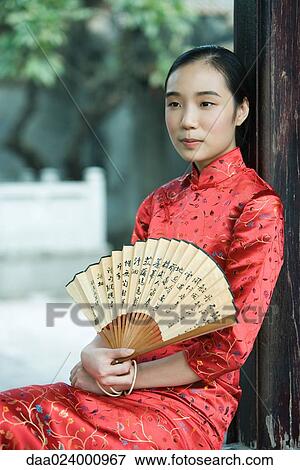 Young woman wearing traditional Chinese clothing, holding fan, portrait View Large Photo Image Stock Photo - Young woman wearing traditional Chinese clothing, holding fan, portrait. Fotosearch