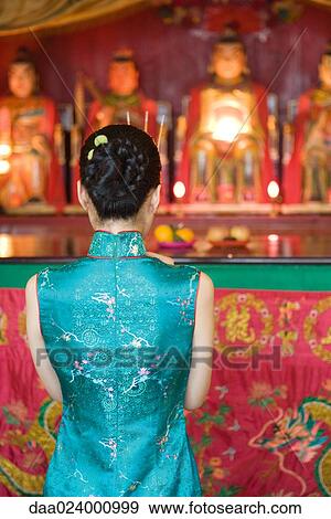 Stock Photo - Young woman wearing traditional Chinese clothing, in front of shrine, rear view. Fotosearch