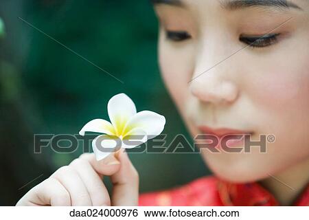 Young woman wearing traditional Chinese clothing, holding flower up View Large Photo Image Stock Photograph - Young woman wearing traditional Chinese clothing, holding flower up. Fotosearch