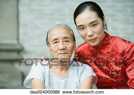 Young woman wearing traditional Chinese clothing posing next to elderly woman, portrait View Large Photo Image Stock Photograph - Young woman wearing traditional Chinese clothing posing next to elderly woman, portrait. Fotosearch