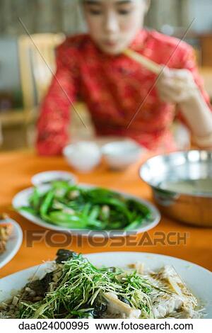 Young woman wearing traditional Chinese clothing, eating with chopsticks, focus on food in foreground View Large Photo Image Stock Photography - Young woman wearing traditional Chinese clothing, eating with chopsticks, focus on food in foreground. Fotosearch
