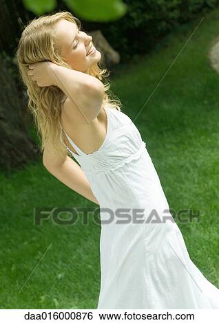 Young woman wearing white dress, hand in hair View Large Photo Image Stock Photograph - Young woman wearing white dress, hand in hair. Fotosearch