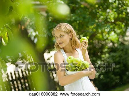 Young woman wearing white dress, holding bowl of apples View Large Photo Image Stock Image - Young woman wearing white dress, holding bowl of apples. Fotosearch
