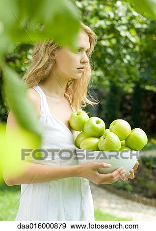Young woman wearing white dress, holding bowl of apples View Large Photo Image Stock Photo - Young woman wearing white dress, holding bowl of apples. Fotosearch